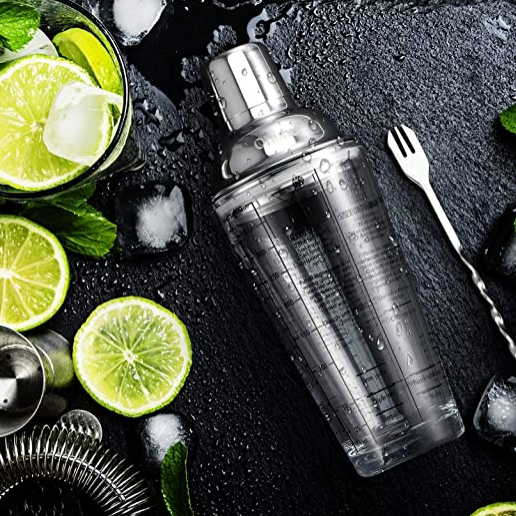 Cocktail shaker with lime slices and ice on a dark surface