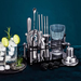 Bartender tool set with glasses and lime garnishes on a dark background