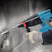 Person using a blue and black hammer drill on concrete.