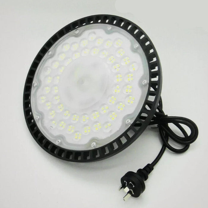 Round industrial light fixture with black casing and visible wiring on a white background