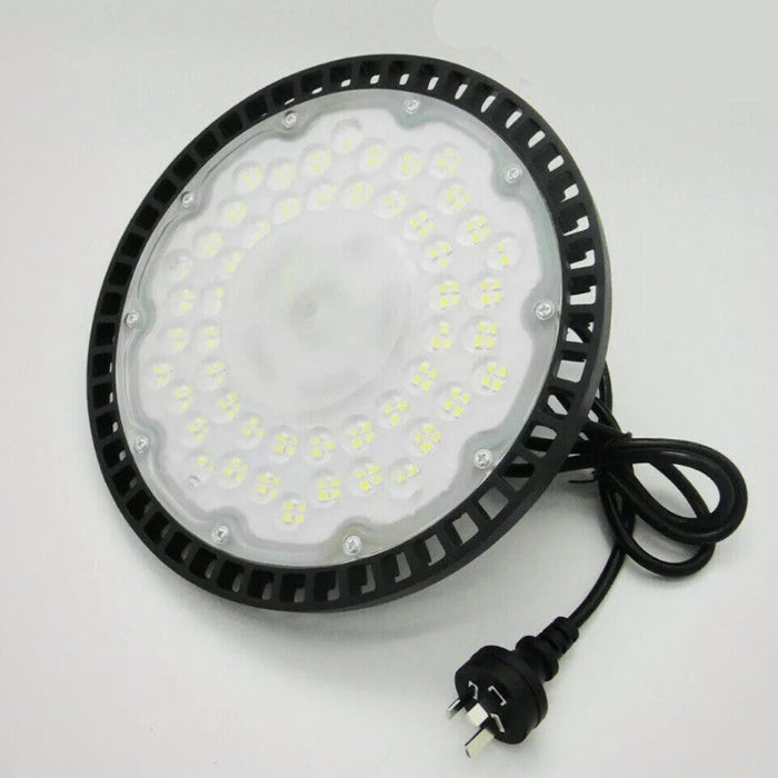 Round industrial light fixture with black casing and visible wiring on a white background