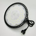 Round industrial light fixture with black casing and visible wiring on a white background