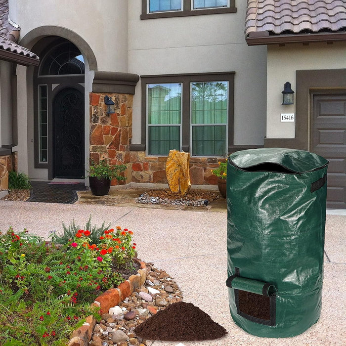 Green garden waste bag on a driveway in front of a house with flowers and rocks.