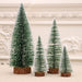 Set of four miniature Christmas trees with wooden bases on a neutral background