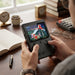 Hands holding and playing a black retro handheld gaming console showing a pixel-art fighting game.