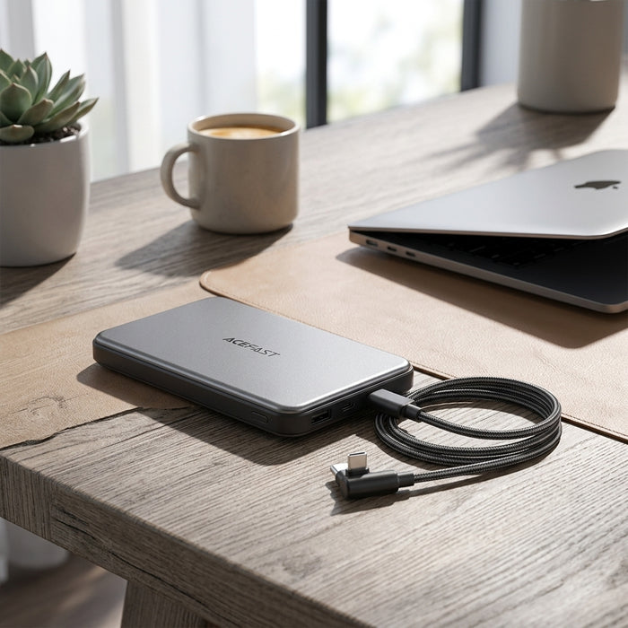 A sleek, ultra-slim silver power bank sits on a modern wooden desk.