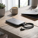 A sleek, ultra-slim silver power bank sits on a modern wooden desk.