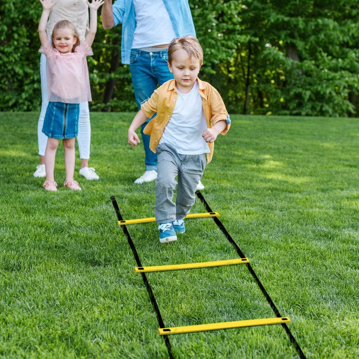Children playing with a yellow agility ladder on a grassy area