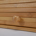Close-up of a wooden drawer with a knob on a light gray background
