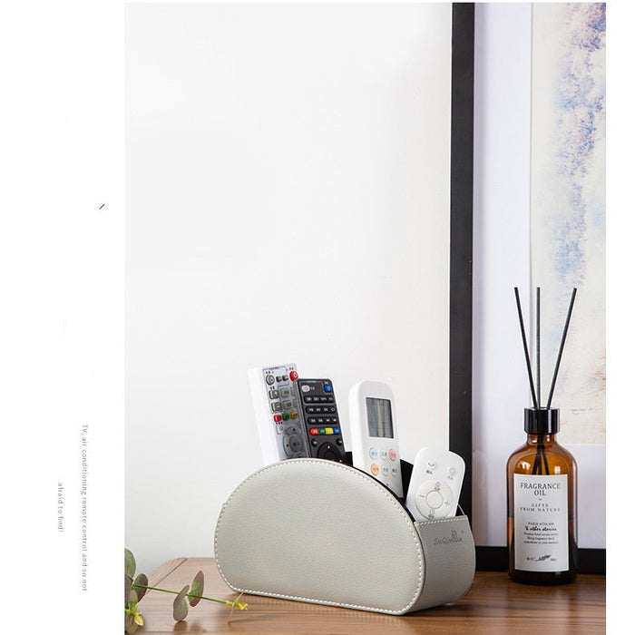 White remote control holder with remotes on a wooden surface next to a bottle of diffuser.