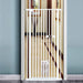 White pet gate in a room with a cat peeking through