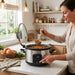 A woman is using a GreenPan Slow cooker in a well-lit kitchen.