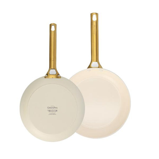 Two cream-colored frying pans with gold handles on a white background