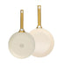 Two cream-colored frying pans with gold handles on a white background