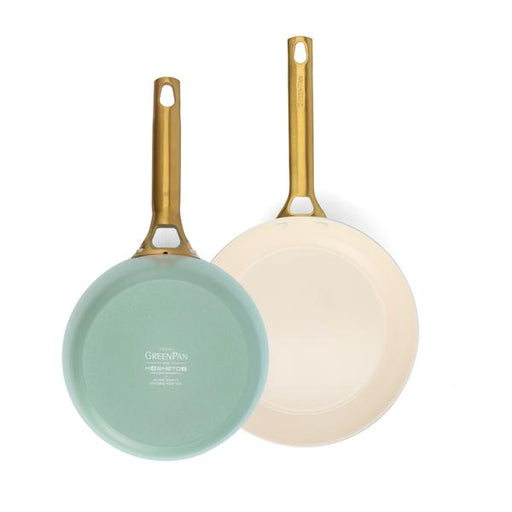 Two frying pans with gold handles on a white background.