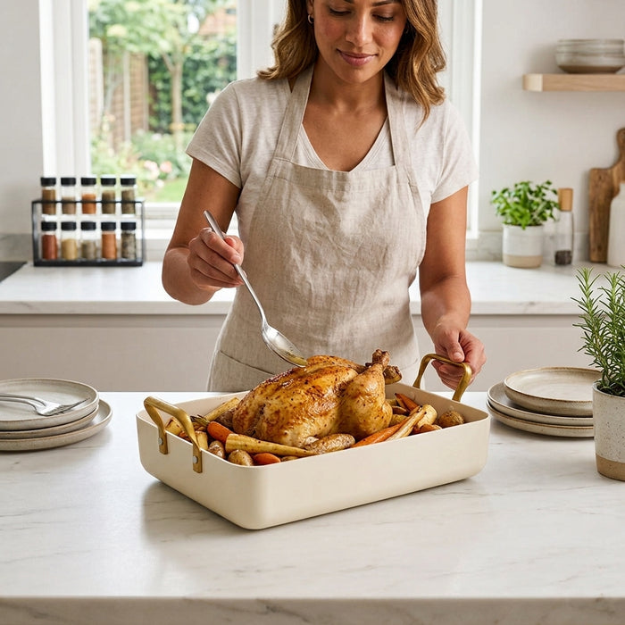 A woman basting a whole roasted chicken and vegetables in a pan.