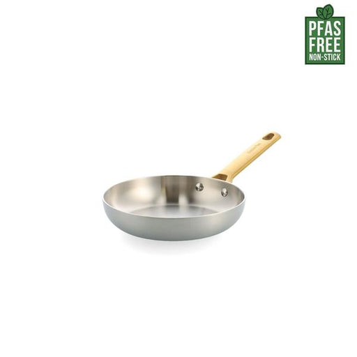 Stainless steel frying pan with a wooden handle on a white background, featuring a PFAS-free label.