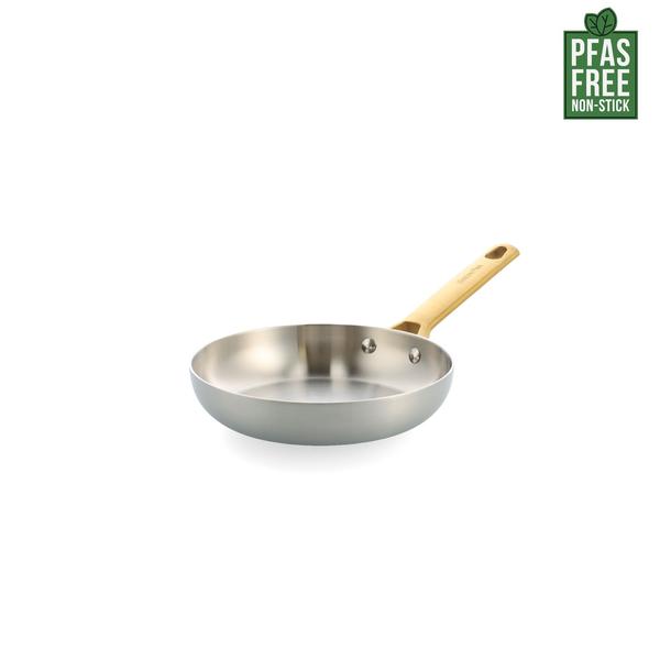 Stainless steel frying pan with a wooden handle on a white background, featuring a PFAS-free label.