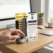 A person puts a Hoco brand battery into a wireless mouse on a desk near two battery packs.