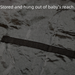 Black strap on a textured gray surface with text indicating it is stored out of baby's reach.
