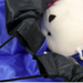 Close-up of a black drawstring bag with a white plush toy on a blue background