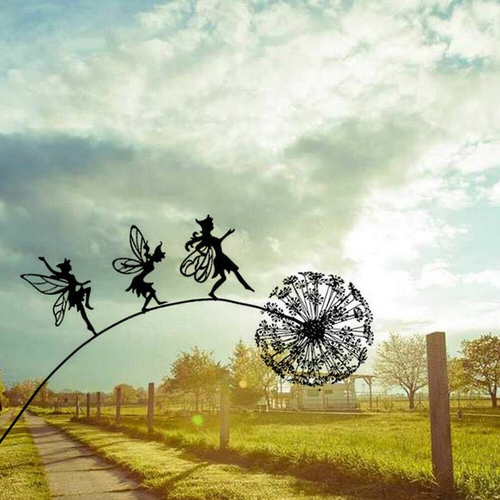 Decorative metal sculpture of fairies on a dandelion against a cloudy sky.