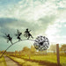 Decorative metal sculpture of fairies on a dandelion against a cloudy sky.