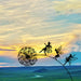 Decorative metal sculpture of fairies on a dandelion against a sunset sky