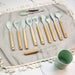 Set of kitchen utensils with wooden handles on a textured fabric surface.