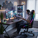 Gamer in an RGB chair playing a futuristic shooter at a custom dual-PC desk setup.
