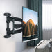 TV mounted on a wall with a scenic display, in a room with a sofa and curtains.
