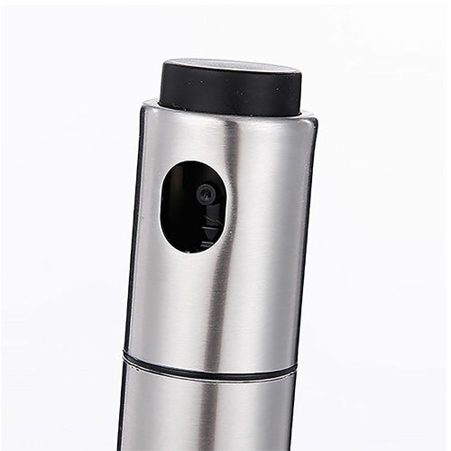 A close-up shot focusing on the top of a stainless steel oil spray bottle, clearly showing the black press button nozzle inside the spray opening and the black plastic cap.