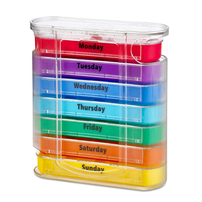 A clear plastic, vertically stacked weekly pill organizer. It contains seven colorful daily trays (Monday through Sunday), arranged in rainbow order, with 'Monday' in red at the top and 'Sunday' in yellow at the bottom. Each tray is clearly labeled with the day of the week in black text.