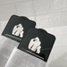 Two black phone screen protectors with a white gorilla graphic, shown partially wrapped in clear protective paper against a white textured background.