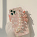 Phone case with floral design and pearl strap held by a person