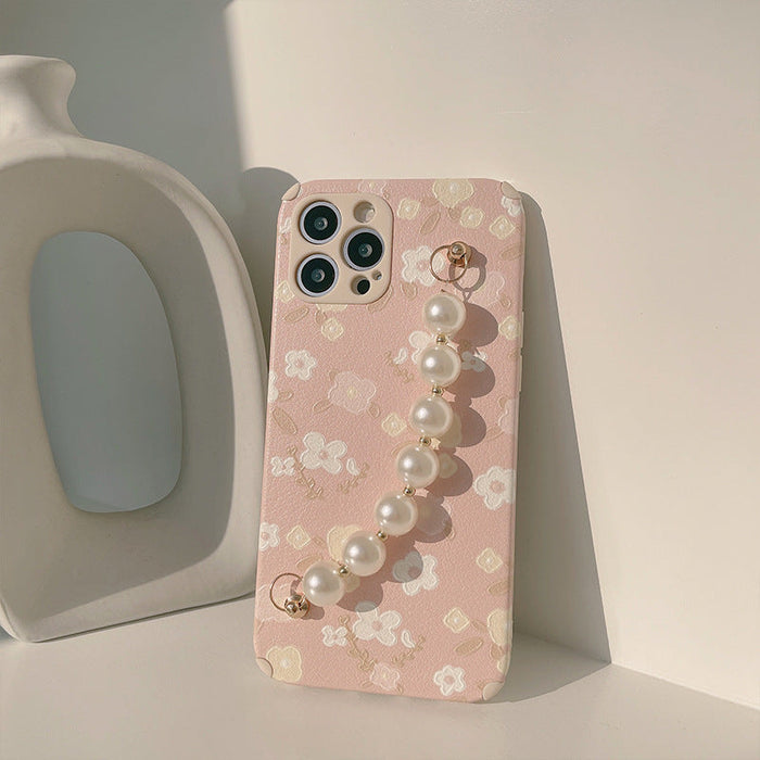 Phone case with floral design and pearl charm on a light background