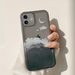 Phone case with moon and cloud design held by a hand on a light background