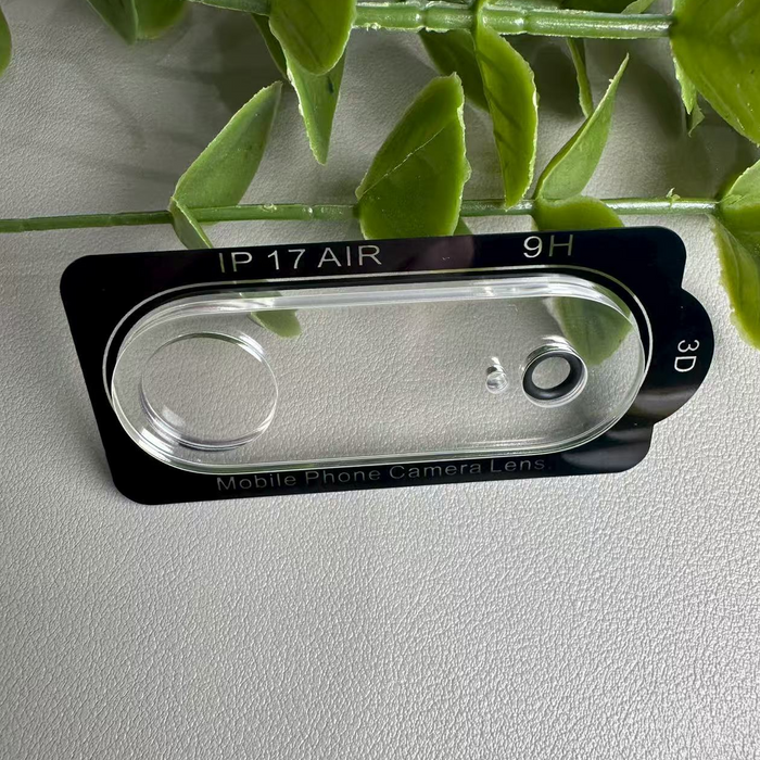 Phone camera lens protector with 'IP 17 AIR' and '9H' text on a light gray background with green leaves.