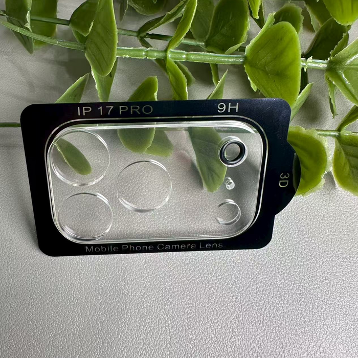 Phone camera lens protector with 'IP 17 Pro' and '9H' text, surrounded by green leaves on a light gray background