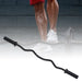 A black Olympic barbell curl bar with knurled grips, laid out on a white background. In the background, there is a silhouette of a person lifting weights.