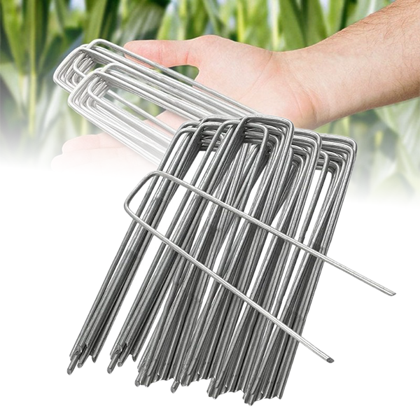 A hand holding a bundle of silver U-shaped landscape staples, with more staples in the background.