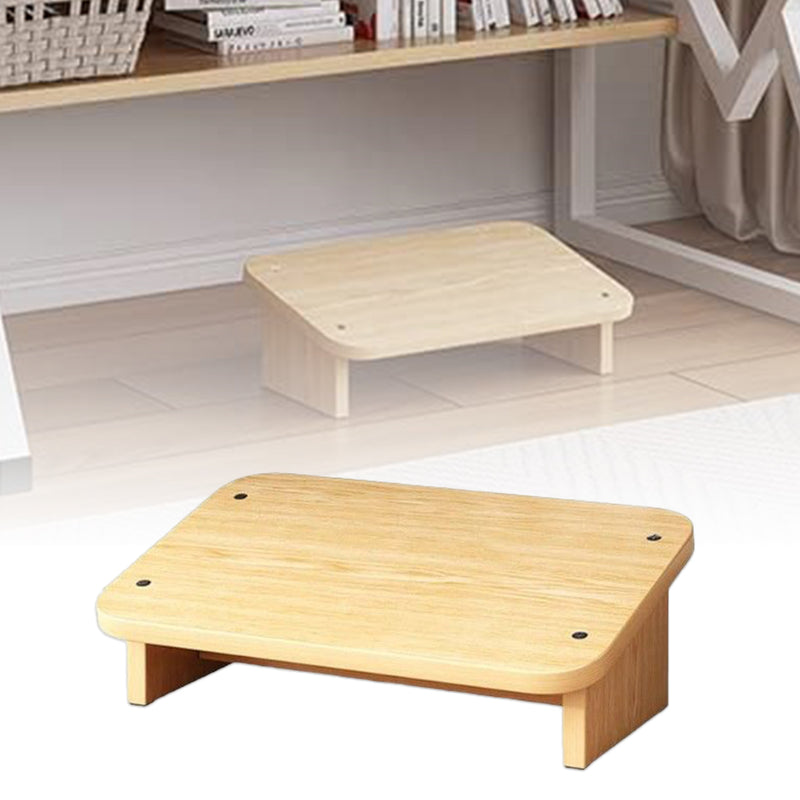 A beige under desk foot rest stool made of MDF, placed under a wooden desk in a home setting.