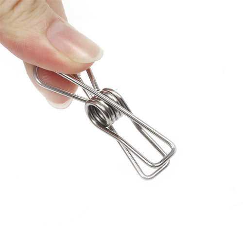 
A close-up shot of a person's fingers holding a single stainless steel mini spring clip (or clothes peg) against a plain white background. The fingers are gripping the top loops of the metal peg.