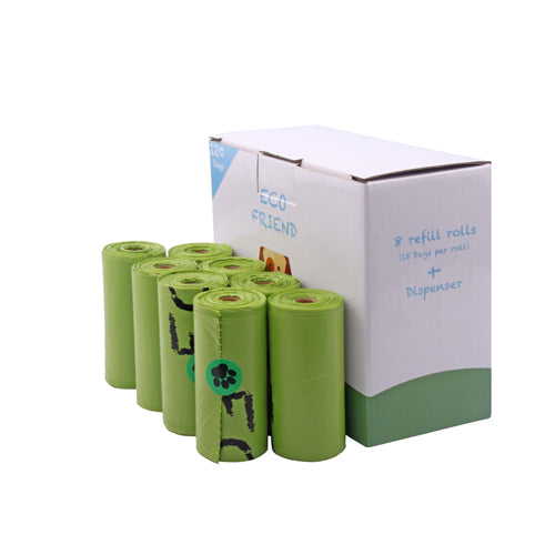 A partially open white and green cardboard box of 'ECO FRIEND' pet waste bags is shown next to eight green refill rolls. The box label indicates it contains '8 refill rolls (15 bags per roll) + Dispenser'. One of the green rolls visible in the foreground has a black paw print printed on the plastic.