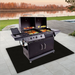 A black under-grill protective deck patio mat placed under a BBQ grill on an outdoor patio with food being cooked on the grill.
