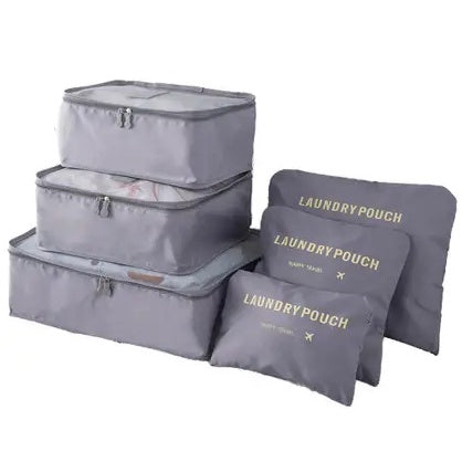 A complete set of three stacked light gray mesh-top packing cubes and three matching flat "LAUNDRY POUCH" bags with gold lettering is displayed, showing a full luggage organizer set.