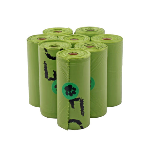 A cluster of ten rolls of bright green pet waste bags standing upright. Black text and a green circle sticker with a black paw print are visible on the rolls.