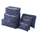 A complete set of three stacked dark blue mesh-top packing cubes and three matching flat "LAUNDRY POUCH" bags with gold labeling is displayed against a white background.