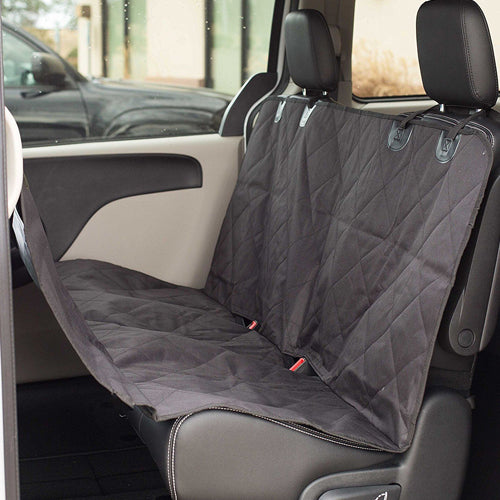 A photo of a black, quilted, waterproof pet hammock/car seat cover fully installed on the rear bench seat of a vehicle. The cover protects the seat and backrest, and the bottom hangs down toward the floor, forming a protective barrier for the pet.